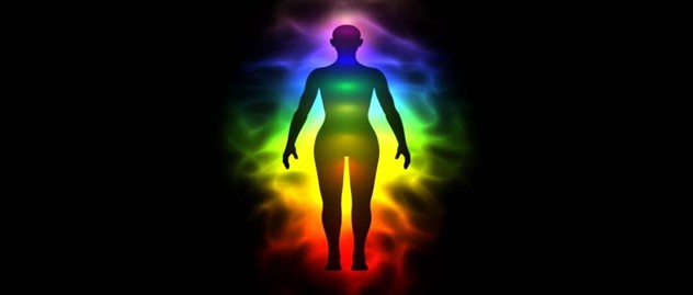 Human silhouette surrounded by glowing rainbow-colored energy fields representing chakras, vitality, energetic balance, and spiritual alignment