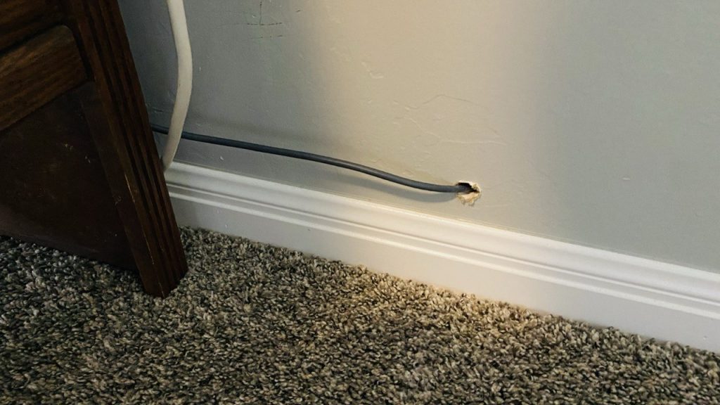 Ethernet cable routed through a wall to create a wired internet connection, reducing reliance on wireless Wi-Fi signals.